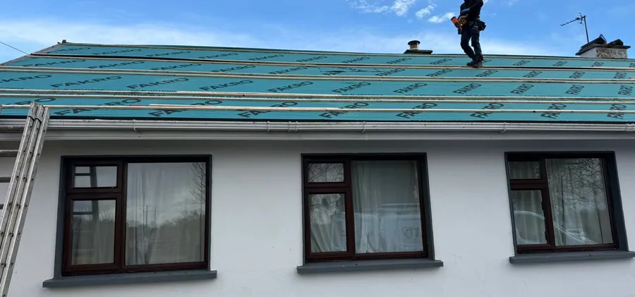 Roofer on the ridge of a bungalow stripped to new breathable membrane and battens, Global Roofing and Guttering, Dublin